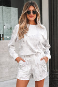 Woman wearing a white camo outfit with sunglasses outdoors.